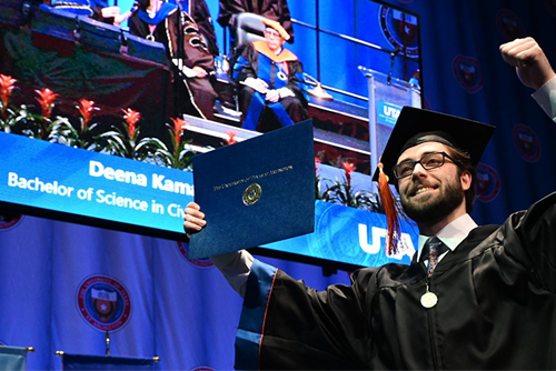 graduate receiving diploma in front of name display