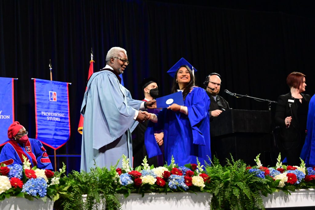 grad smiling while receiving diploma