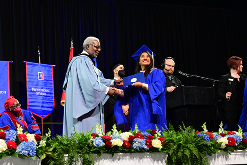 Grad smiling while receiving diploma